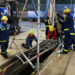 Eine der Stationen demonstrierte den Aufbau eines Dreibocks, der aus Komponenten des Einsatz-Gerüstsystems (EGS) über einer Grube errichtet wurde. Anschließend retteten die Teilnehmer eine Person mit dem Rollgliss, einem Rettungs- und Abseilsystem nach dem Flaschenzugprinzip, aus der Grube. (Foto: THW/Michael Belser)