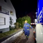 Die ehrenamtlichen Katastrophenschützer in ihren blau-gelben Einsatzanzügen laden an einem dunklen Herbstabend ihr schweres Werkzeug von dem großen Gerätekraftwagen ab. (Foto: THW/Sandro Wiggerich)
