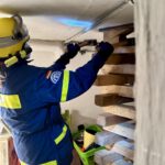Im Keller entsteht ein Kreuzstapel aus Kanthölzern. Zum Schluss werden Keile gegeneinander eingeschlagen, damit zwischen Holz und Kellerdecke kein Spalt bleibt. (Foto: THW/Sandro Wiggerich)