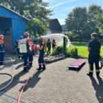 Jugendliche von THW und Feuerwehr kühlen gemeinsam eine Gasflasche mit Wasser – konzentriertes Arbeiten an der Übungsstelle. (Foto: THW/Michael Belser)
