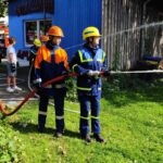 Jugendliche von THW und Feuerwehr kühlen gemeinsam eine Gasflasche mit Wasser – konzentriertes Arbeiten an der Übungsstelle. (Foto: THW/Michael Belser)