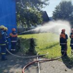 Jugendliche von THW und Feuerwehr kühlen gemeinsam eine Gasflasche mit Wasser – konzentriertes Arbeiten an der Übungsstelle. (Foto: THW/Michael Belser)